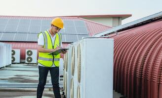 man in a yellow vest is writing on a clipboard while standing on a roof photo