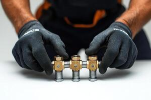 A man in black gloves holding two brass fittings photo