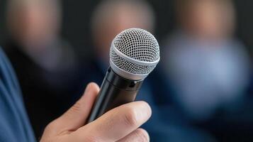 A person holding a microphone in front of a group of people photo