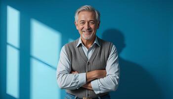 smiling man in a grey vest and blue jeans. He stands against blue background with his arms crossed over his chest. The light from window is visible on background.The photo is made in calm colors