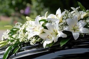 A beautiful arrangement of white lilies and greenery decorates the top of a black hearse, symbolizing respect and remembrance for a loved one during the funeral service photo