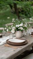 A charming outdoor dining arrangement features a rustic wooden table adorned with natural elements. Fresh white flowers in a simple vase create a serene atmosphere among glass jars and wooden plates photo