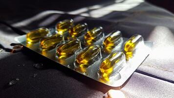 Closeup view of transparent gel capsules filled with oil, showcasing their design and texture. These dietary supplements, emphasize their relevance in promoting health. photo