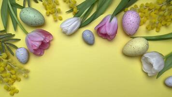 Easter eggs and spring flowers creating festive border on yellow background video