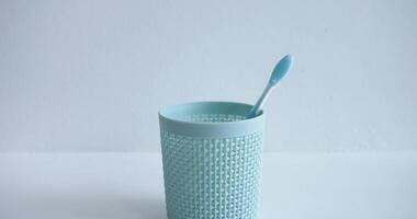 A hand lowers colorful plastic toothbrushes into cup one by one, symbolizing hygiene. A clear depiction Illustrates importance hygiene. Hygiene is highlighted with every toothbrush placed. video