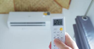 A hand presses button air conditioner remote several times lower temperature display. Seeking comfort, adjusts climate ideal temperature. Comfort through technology. Technology enhances comfort. video