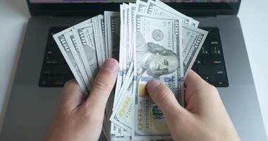Hands shuffle and throw 100 us dollar bills onto keyboard an open laptop, ultimate symbol winning. vividly captures euphoria lavish rewards associated with winning, thrill prosperity winning brings. video