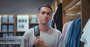 Man searching trendy style in modern boutique, man seeking style that complements personal taste, man refining style through thoughtful browsing, ideal for fashion and retail marketing. video