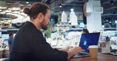 Elearning developer. Programmer creating e-learning modules educational content on his computer. Man sitting in cafe looking at screen and typing code. E-learning developer found a solution of issue video