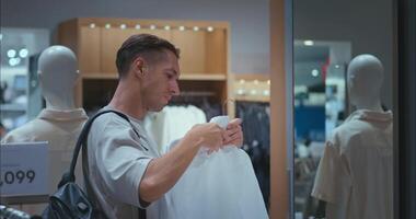 Man choosing casual clothes in stylish store, man choosing comfortable fit for everyday wear, man choosing best option for personal style, perfect for modern retail and marketing visuals. video