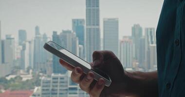 Man using smartphone to scan crucial updates, smartphone helping man track shifting tasks in sprawling city, smartphone illustrating fast-paced digital workflow, ideal for urban business themes. video