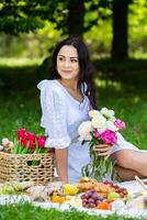 Elegant Woman Sitting on a Picnic Blanket Under a Tree photo
