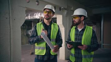 Two Caucasian men workers mechanics builders guys discuss building employees colleagues planning project manufacturing in factory males teamwork architects inspect construction conversation industry video