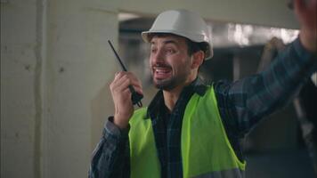 Caucasian man foreman control construction process manager male guy builder talking speaking on radio digital device walkie talkie professional contractor civil engineer architect repairman building video