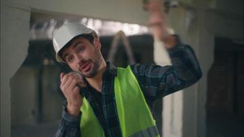 Caucasian technician builder pointing constructor speaking walkie talkie radio architect instruct in construction man foreman waving hand male engineer gesturing control building inspection production video