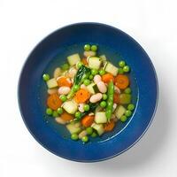 Homemade Spring Minestrone soup served in a rustic blue bowl, isolated with shadow. A comforting and nutrient-rich meal with seasonal veggies and pasta photo