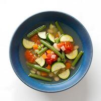 Healthy Spring Minestrone soup with fresh greens and beans in a blue dish, top view. A light and hearty soup packed with springtime flavors photo
