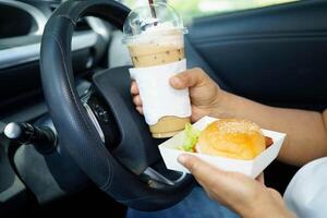 Asian woman driver hold and eat hamburger foo photo