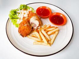 Chicken cordon bleu with french fries and sauce served on a white background photo
