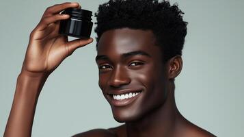 Male model with smiling expression holding black body balm in hand above head. 7 photo