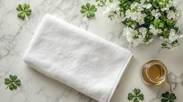 A blank white towel laying with a golden honey jar and clovers lying around it. 15 photo