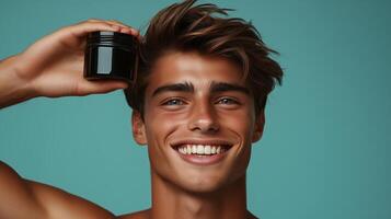 Male model with smiling expression holding black body balm in hand above head. 8 photo
