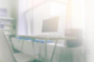 Blur office background with working desk and computer. Light is coming through the window. photo