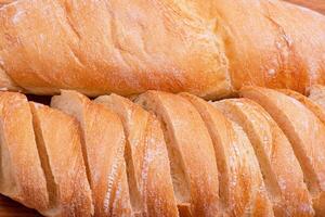 Wheat baguette sliced and whole close-up as a background. photo