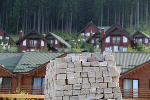 Pile Of Square Construction Bricks In Front Of Wooden Houses photo