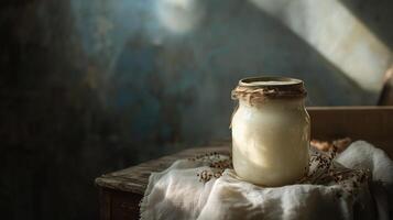 Rustic jar of homemade plant-based yogurt sits on a weathered table bathed in soft light indoors photo