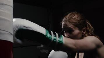 Female fighter during an intense boxing workout throws strong and fast punches on a punching bag with precision video