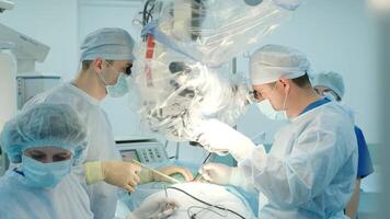 surgeons perform an operation and look through a microscope video