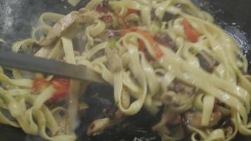 a dish of noodles and meat is cooked in a pan video