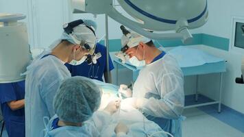 surgeons perform an operation and look through a mobile microscope video
