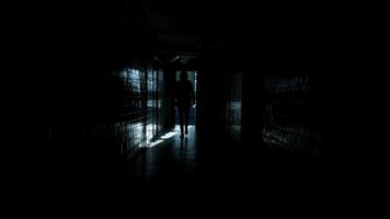 Man walks along a dark long corridor. Abandoned building, dark corridor, dark silhouette of a man, light in the doorway, ruins, broken windows, rust, unfinished 3 video