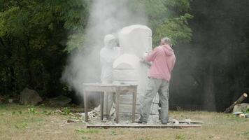 two sculptors create a statue of stone with a hammer and grinder 3 video