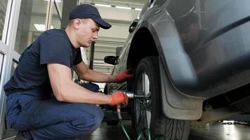 car mechanic screwing or unscrewing car wheel of lifted automobile at repair service station 7 video