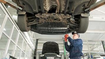 Auto mechanic working underneath car lifting machine at the garage. Auto repair shop, Car service, repair. 4 video