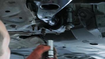 Auto mechanic working underneath car lifting machine at the garage. Auto repair video
