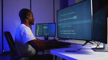 Focused African American programmer coding on multiple monitors video