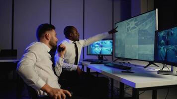 Two security officers monitoring CCTV and communicating via radio video