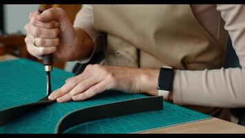 Hands of a woman and a man with tools for leather processing in a workshop, partnership video