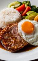 A delicious meal featuring a perfectly cooked fried egg atop a juicy slice of glazed steak is accompanied by a portion of fluffy white rice. photo