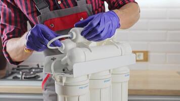 plumber works with a replaceable water filter. Replacement of the carbon filter in the water purification system. Man removed the case with the old filter. video