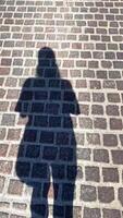 The shadow of a man walking along a path of stones under the bright sun in summer video
