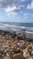 View of the cobblestone shore, mountains and ships in the distance, sea waves video