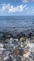 View of the vast ocean, horizon between ocean and sky with white clouds, mountains in the distance on an island video