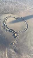 Heart drawn on the wet sand of the beach, water lapping the beach from all sides video