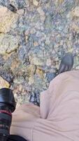crossing mountain creek in shorts, ankle boots with camera. video