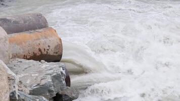 mountain river water flowing through steel pipes under temporary. video